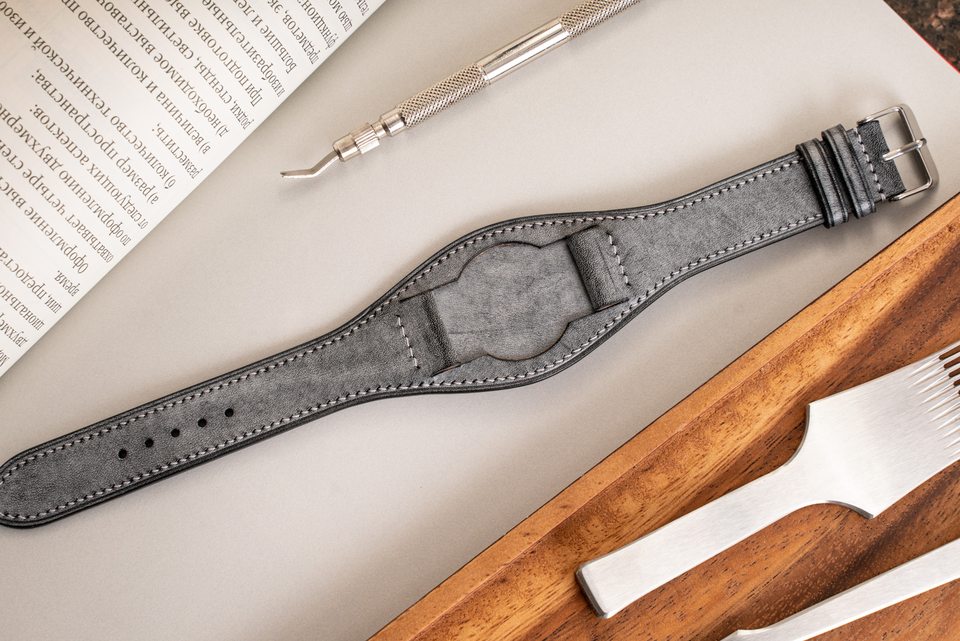 Grey Bund strap beside an open book, showing its pointed taper.