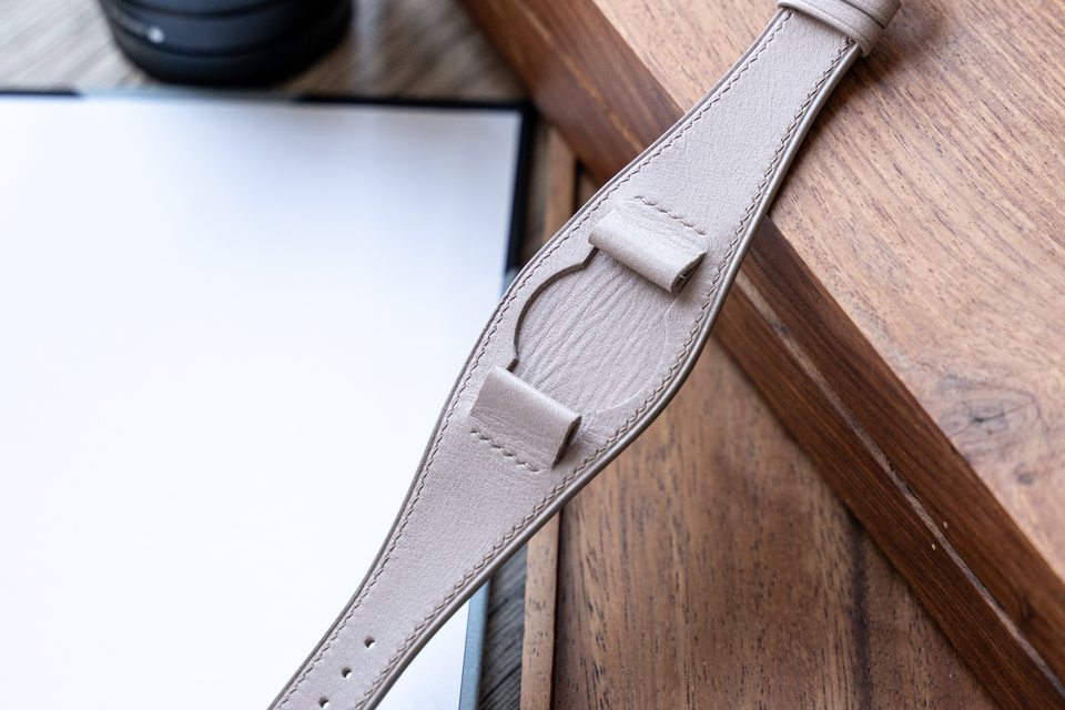 Pale stone Bund strap resting across wooden trays, with its centre exposed.