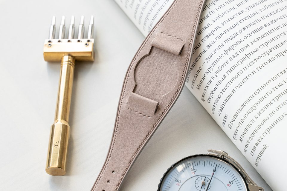 The stone Bund strap laid across a book beside workshop tools.