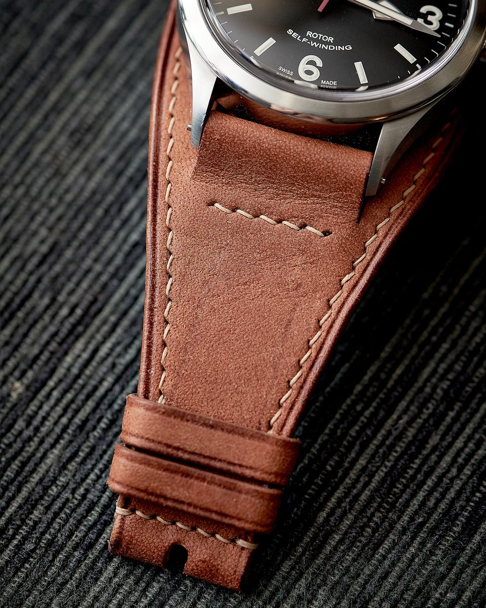Close-up of the dark watch dial, tan Bund backing and light stitches.